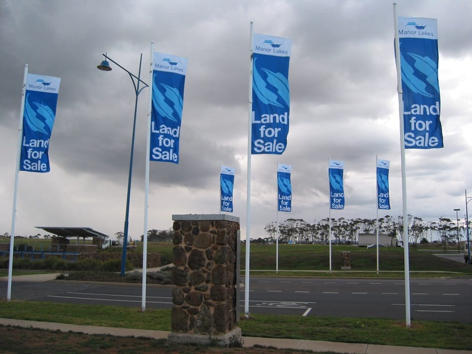 Custom flags on flag poles to promote lands for sale